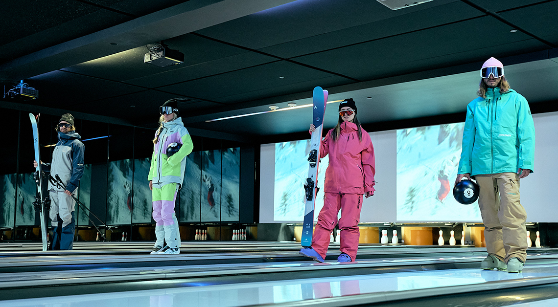 Skiers wearing outerwear in a bowling alley