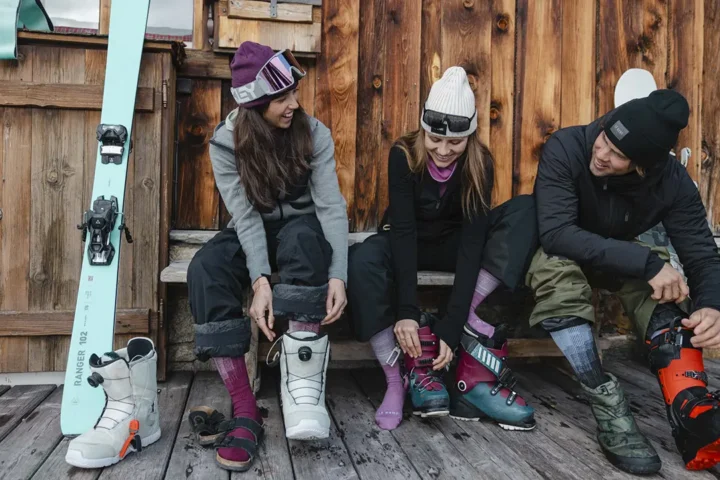 A group of skiers putting on ski gear wearing LE bent socks